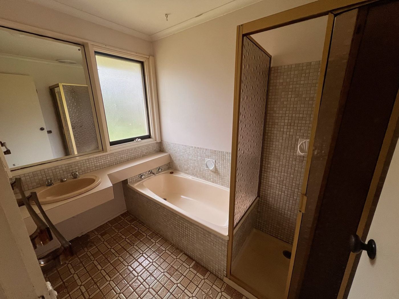 Bathroom before renovation, with old bath and mosaic tiles